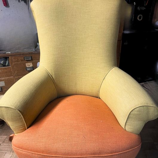 Poltrona di design vintage restaurata e rimodernata con tessuto giallo senape e seduta arancione.