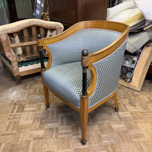Poltrona stile Impero restaurata e rifoderata con un elegante tessuto jacquard blu e micro-pattern geometrico dorato.