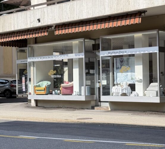 Vetrina esterna dello showroom Mythos Creazioni d'Interni (Mythos Deco) in Via Madonnetta 15 a Lugano, con esposizione di poltrone artigianali e soluzioni di arredamento su misura.